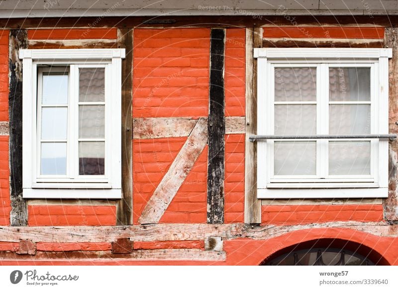 Close-up of the facade of a red-painted half-timbered house with two windows and clearly visible beam construction Facade painted red Half-timbered house