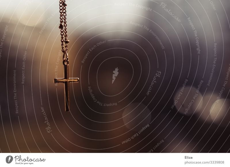 A golden cross crucifix hangs on a chain in front of a blurred background in the church Crucifix Church Belief Chain Gold Christian cross Religion and faith