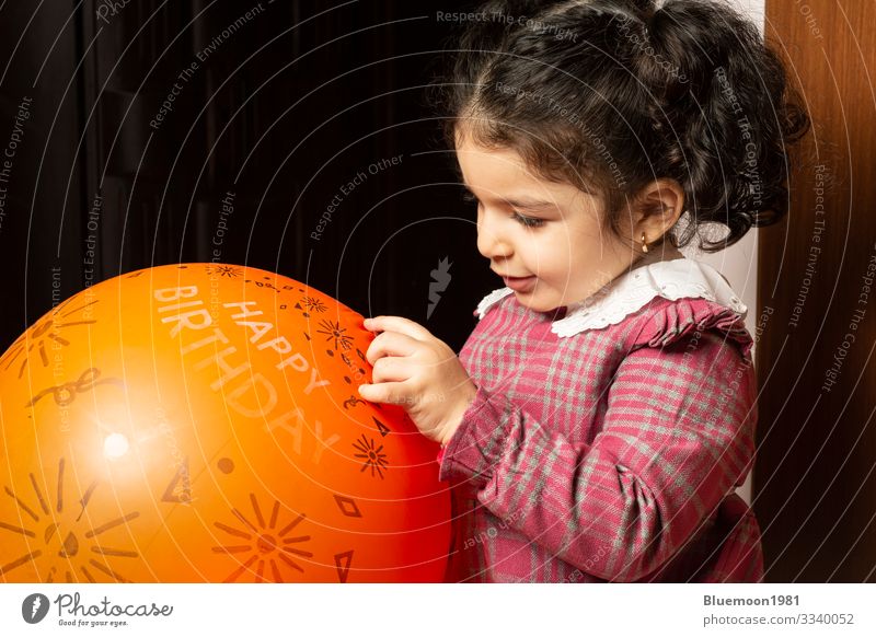 A little girl child is playing with orange birthday balloon Lifestyle Design Joy Face Playing Feasts & Celebrations Child Industry Human being Girl Infancy 1
