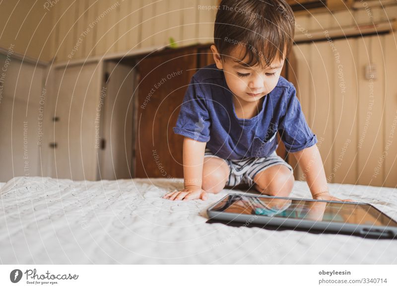 cute young mixed race boy playing with an electronic device Joy Happy Playing Reading Summer Garden Bedroom Child Computer Technology Internet Human being