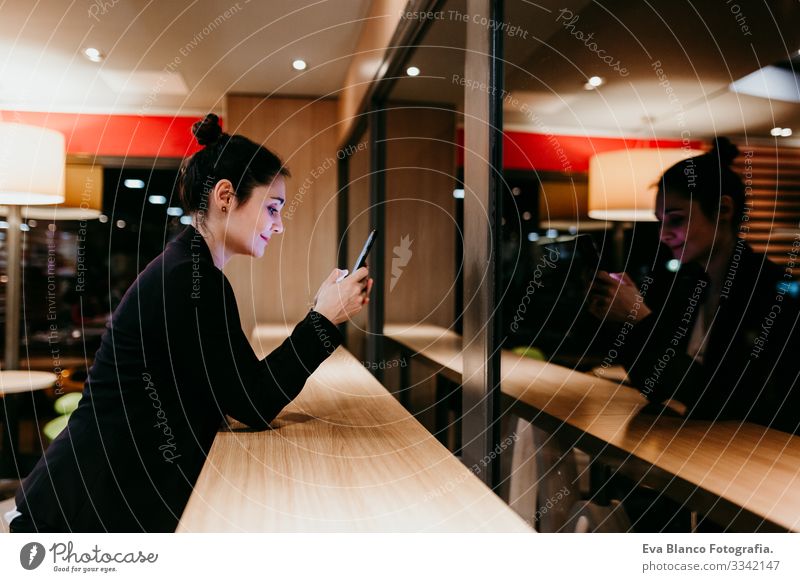 young woman using mobile phone in a cafe or restaurant indoors. Technology and lifestyle Woman Cellphone Interior shot Restaurant Café Window Businesswoman