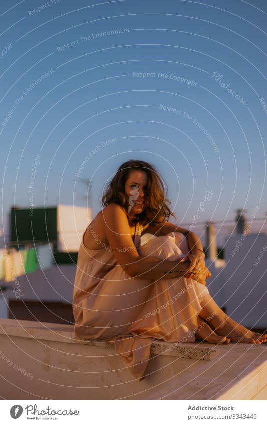 Carefree woman on vacation seeing sunset on balcony summer sky heaven sitting resting relax dress silk carefree freedom young female lady dusk resort tropical