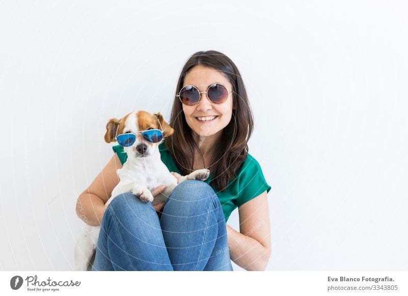 Beautiful young woman playing with her little cute dog at home. Lifestyle portrait. Love for animals concept. white background. Both wearing sunglasses Dog Home