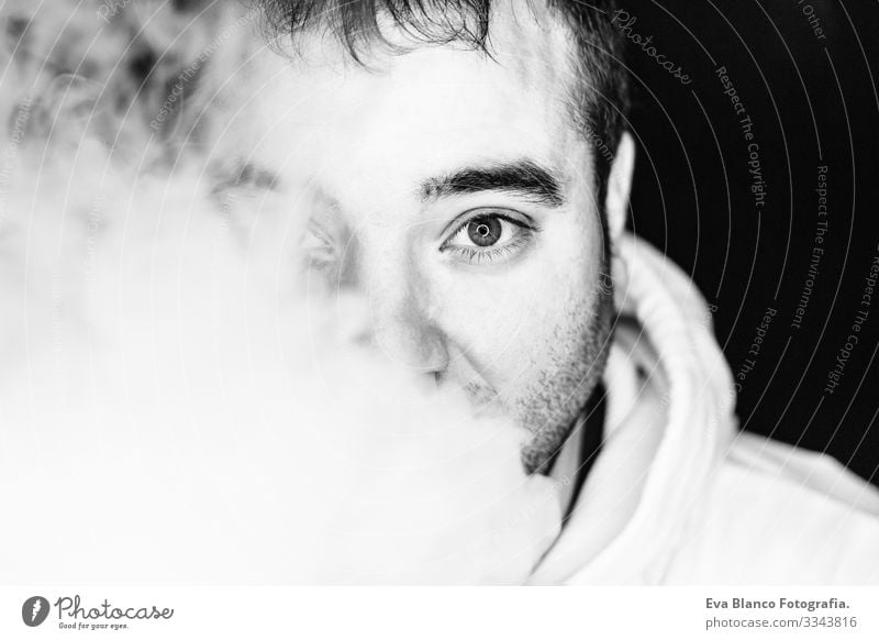 Portrait of a young man smoking, studio shooting, black and white , close up view. led ring reflection in the eyes Head Dark White Human being Man Cigarette Bad