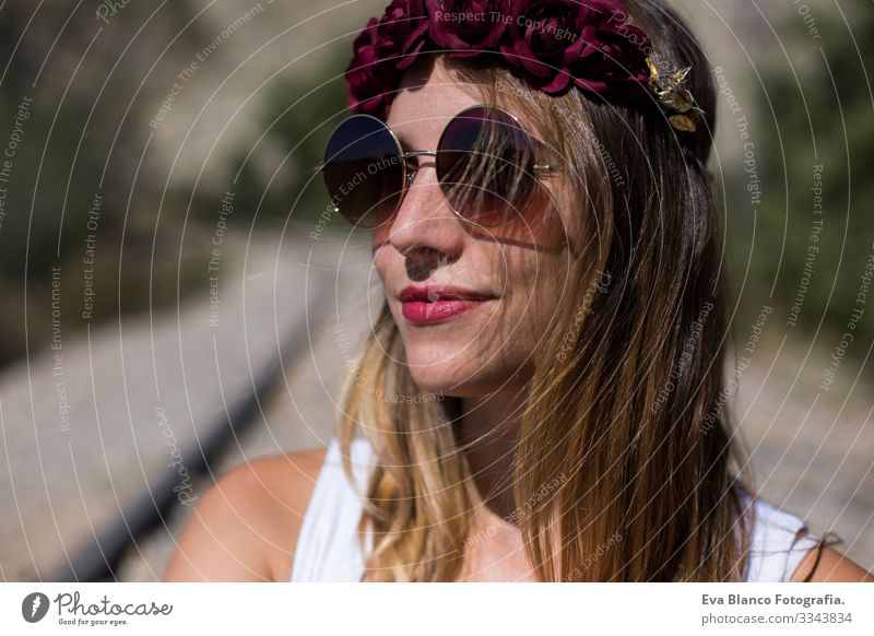 close up portrait of a young beautiful woman wearing modern sunglasses and a red roses wreath on her head. Outdoors. Sunny. Lifestyle Freedom Beauty Photography