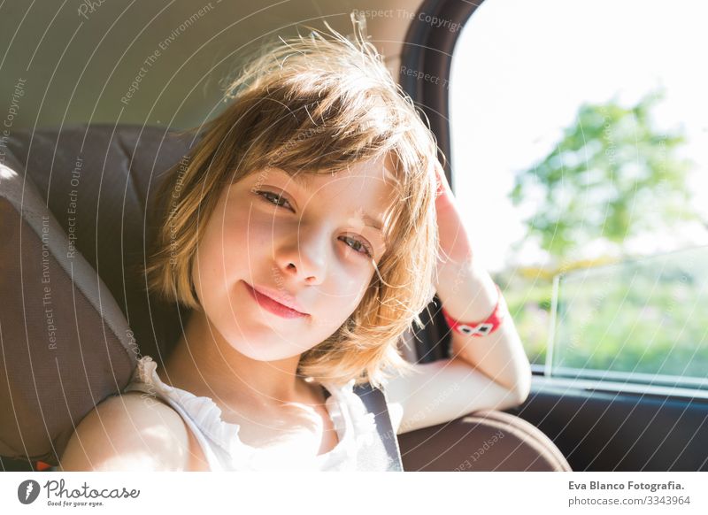 cute small child, blonde girl, in car seat wearing seat belts happy is going to go in the path of the road, sun glare reflected Belt Summer Small Child