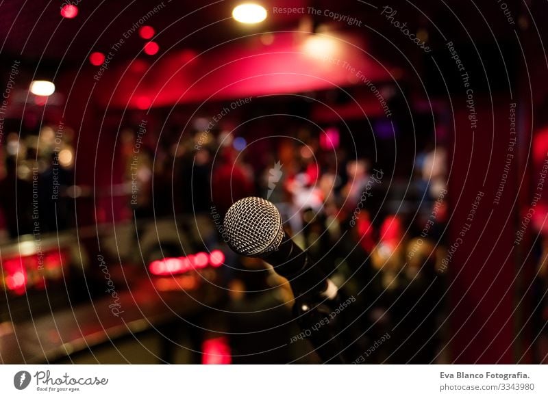 microphone on a stand up comedy stage with colorful bokeh , high contrast image. Microphone Party Night Club Human being crowd Christmas & Advent Red