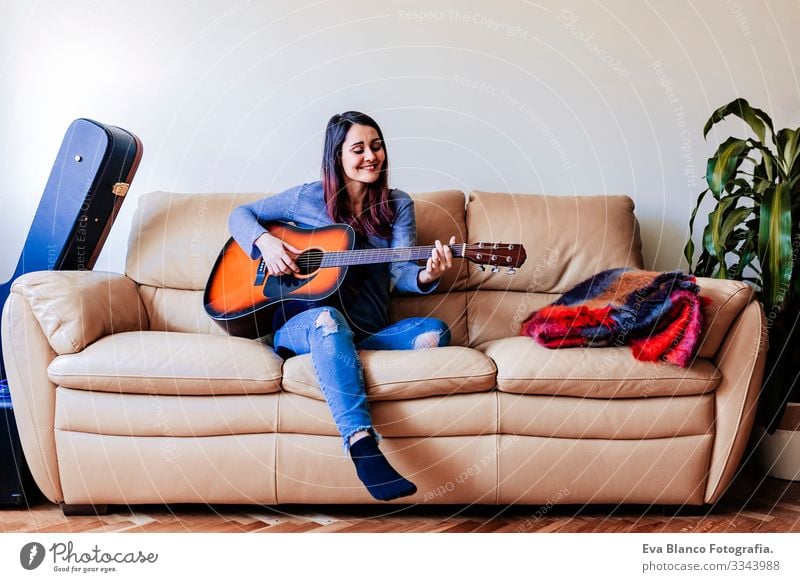 Young beautiful woman playing guitar standing on the sofa. Music concept Portrait photograph Drive Home Inspiration Bedroom Band Electric Rock Expression Guitar