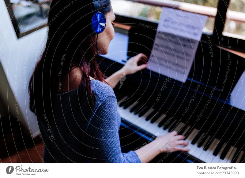 young woman holding playing piano by reading a music sheet. Music concept indoors. Back view Style Human being Key note Lessons Caucasian Press Chord Woman