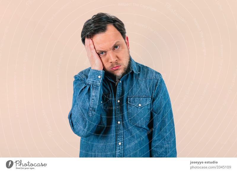 Young man with expression of extreme tiredness and sadness. Denim shirt and isolated pink background. 30-40 years advertisement advertising apathy attitude