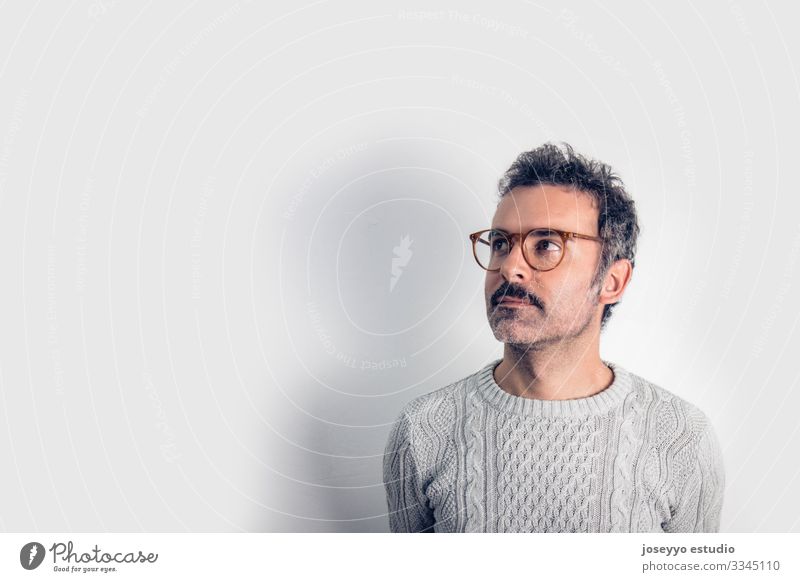 Portrait of  handsome and brown thinking man with mustache, glasses and  gray sweater. Gray background. Copy space adult arms attractive brain casual challenge