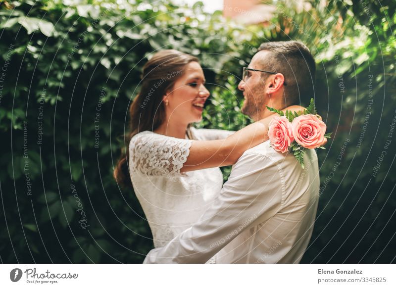 Newlywed couple looking at each other hugging and dancing. Garden Feasts & Celebrations Wedding Woman Adults Man Rose Bouquet Kissing Love Embrace Emotions
