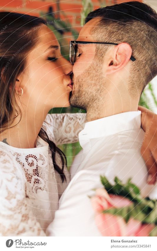 newlywed couple with close eyes and kissing Feasts & Celebrations Wedding Woman Adults Man Fingers Rose Bouquet Kissing Love Emotions Romance Eternity Tradition