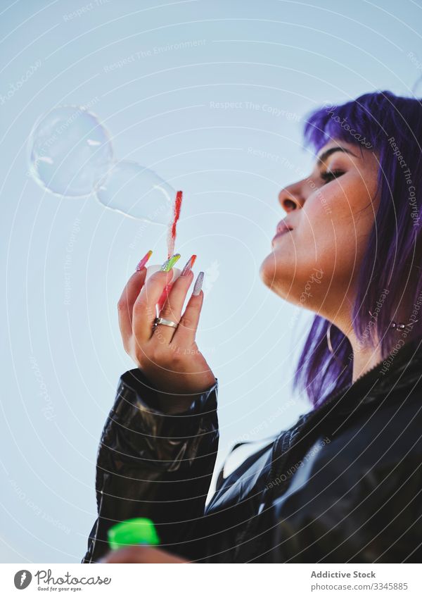Woman blowing bubbles in bright day woman purple stylish funny cute soap cheerful laughing lovely hairstyle playing joy having fun healthy creativity playful