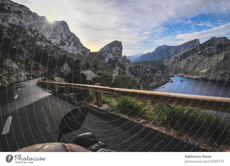 Faceless tourist riding motorbike on road surrounded by mountains man ride travel canyon lake landscape trip male tourism rock nature valley asphalt water
