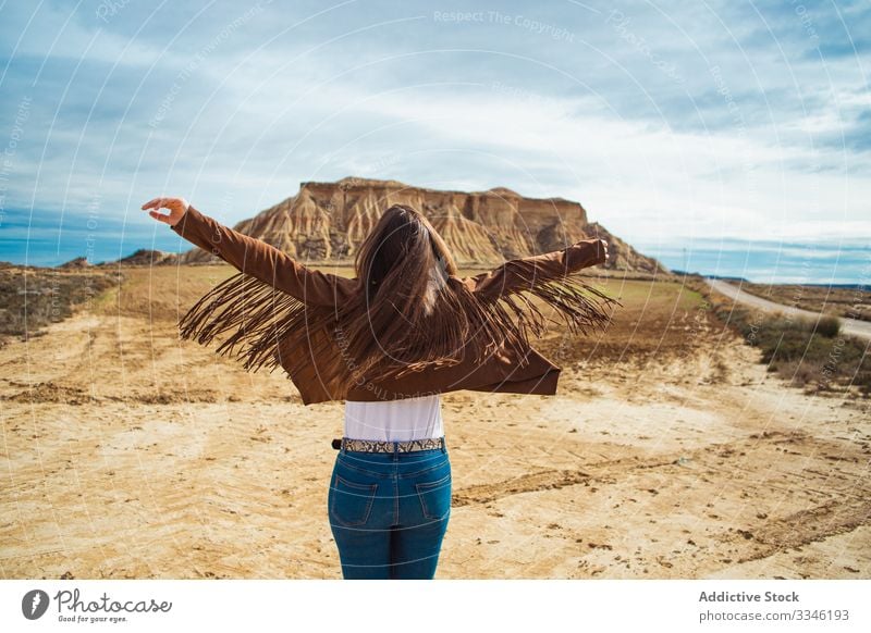 Unrecognizable female enjoying trip in desert woman travel vacation raised hands casual stylish summer tourism blue sky nature lifestyle holiday young landscape