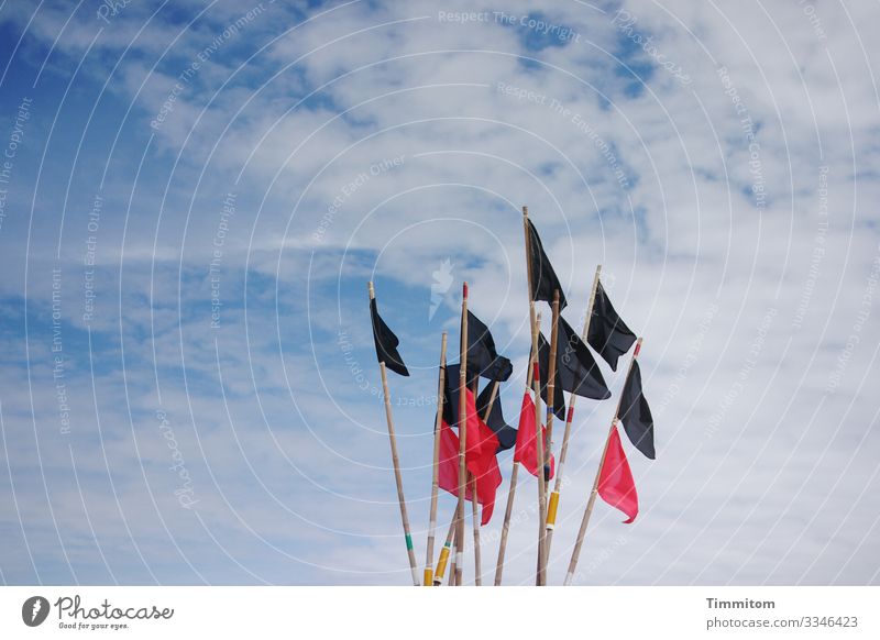 Black and red flags of a fishing boat in front of a cloudy sky - a