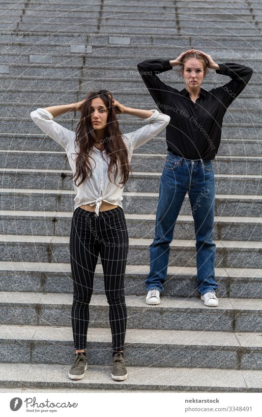 Two Women Posing on Steps with Hands in Hair Woman Adults Youth (Young adults) Youth culture Contentment dancing girls steps hands in hair arms raised staircase