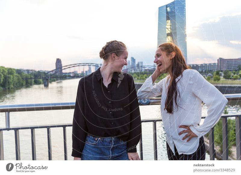 Two Women Making Eye Contact on Bridge with City Background Woman Adults Friendship Youth (Young adults) Skyline Smiling Love Happiness girls real life