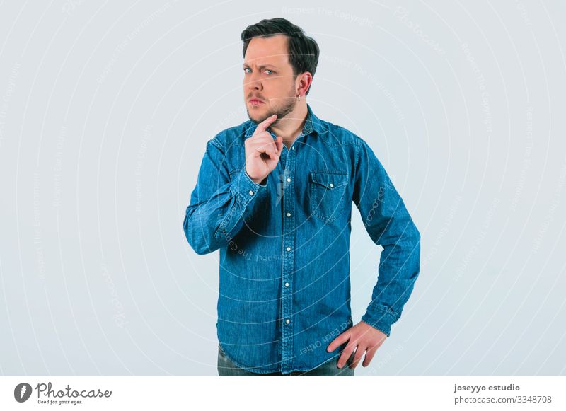 Young man with expression of disagreement and firmness. Denim shirt and isolated gray background. 30-40 years advertisement advertising analytical attitude