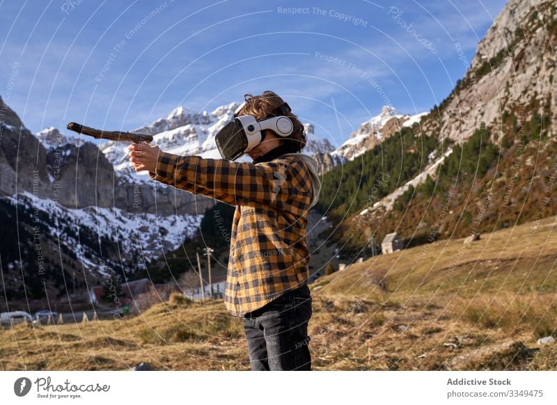 Boy standing on stone in VR glasses against mountain boy vr nature valley virtual stick reality headset modern device entertainment explore terrain technology
