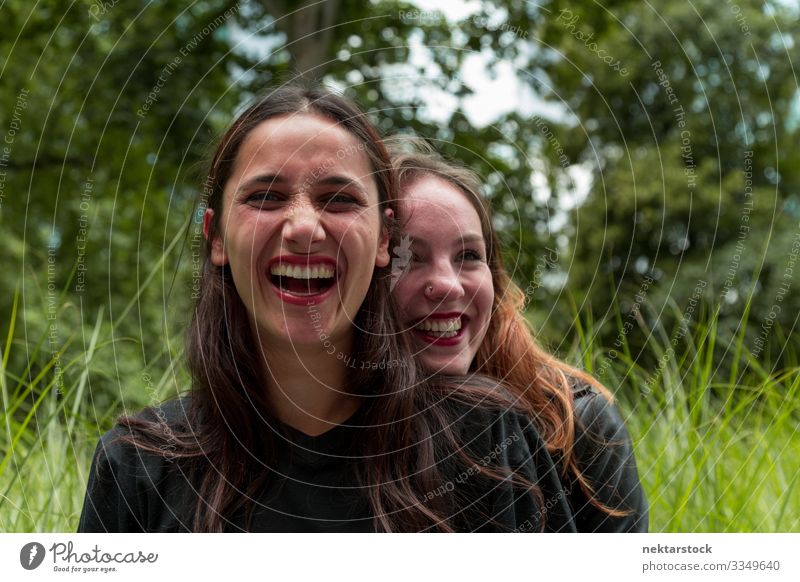 Two Girlfriends of Different Races Laughing Outdoors Joy Beautiful Woman Adults Friendship Youth (Young adults) Nature Grass Park Embrace Happiness Together