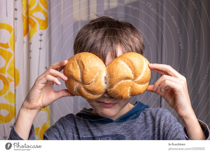 Child with holds two buns in front of his eyes Food Bread Roll Nutrition Eating Healthy Eating Playing Face by hand 1 Human being Eyeglasses Elections