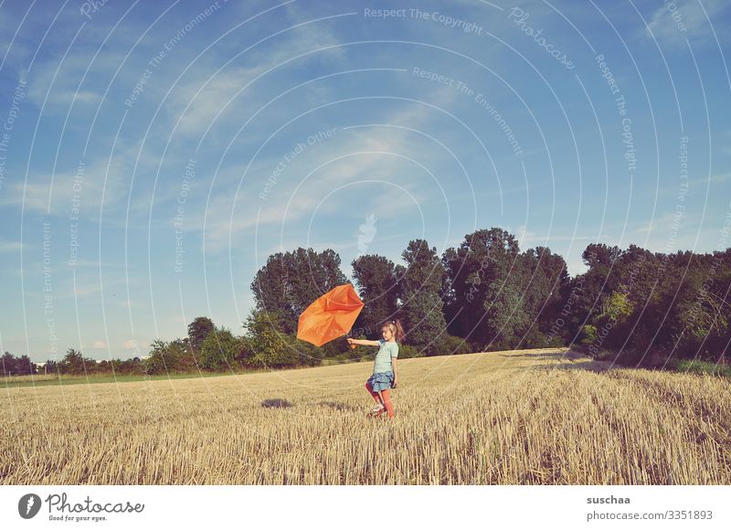 child stands on the straw chopper and holds a broken umbrella against the wind Child girl acre Grain field Summer Landscape Nature Umbrella Broken Orange