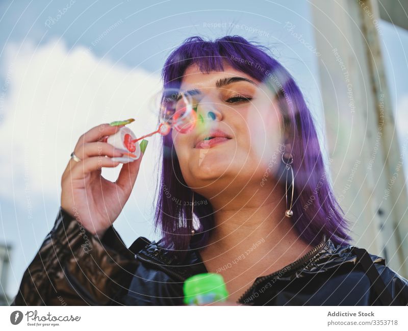Woman blowing bubbles in bright day woman purple stylish funny cute soap cheerful laughing lovely hairstyle playing joy having fun healthy creativity playful