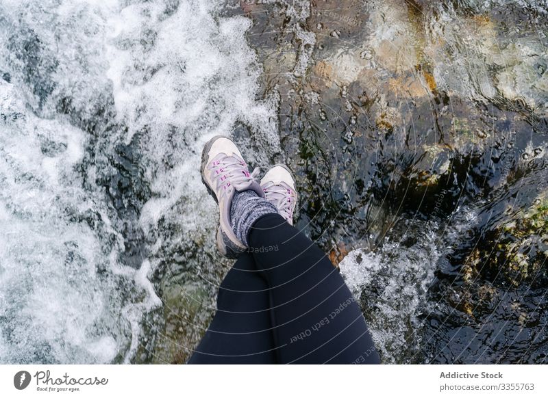 Tired tourist with backpack sitting dangling legs on bridge above mountain river village gangling legs using travel nature house peak landscape architecture