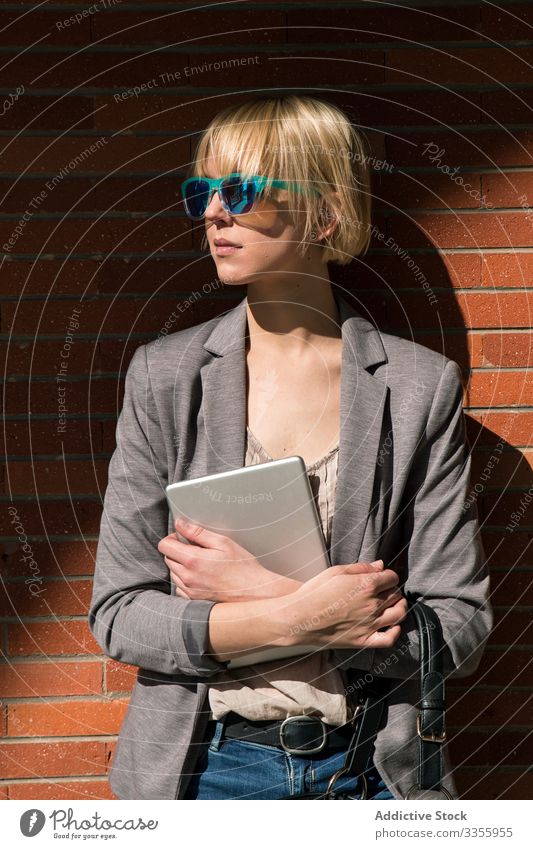 Businesswoman with tablet at wall businesswoman stylish young leaning brick wall female professional person beautiful attractive sunglasses looking away