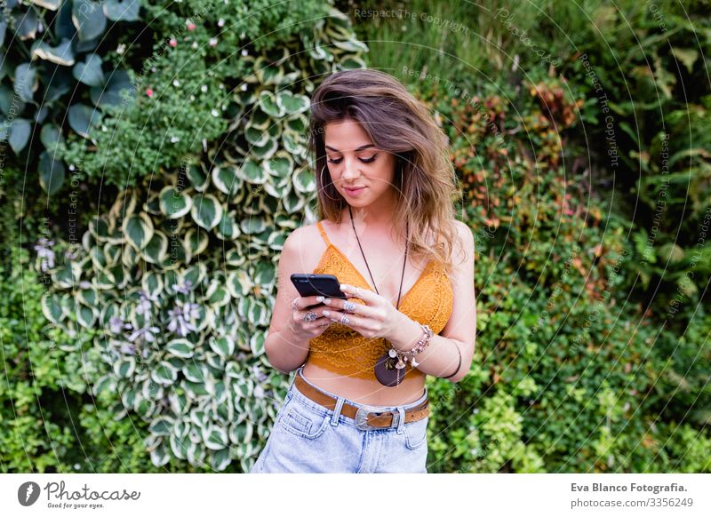 young blonde beautiful woman at the street using mobile phone and smiling. Lifestyle outdoors. Summertime, Green background Smart Town Happy Human being Smiling