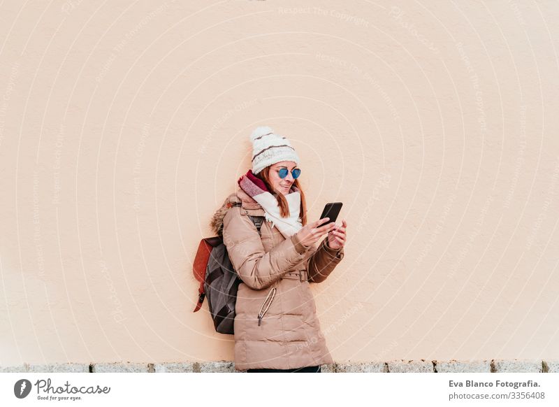 woman using mobile phone over yellow wall background. Technology and winter concept Woman Exterior shot City Wall (building) Winter Cellphone Yellow