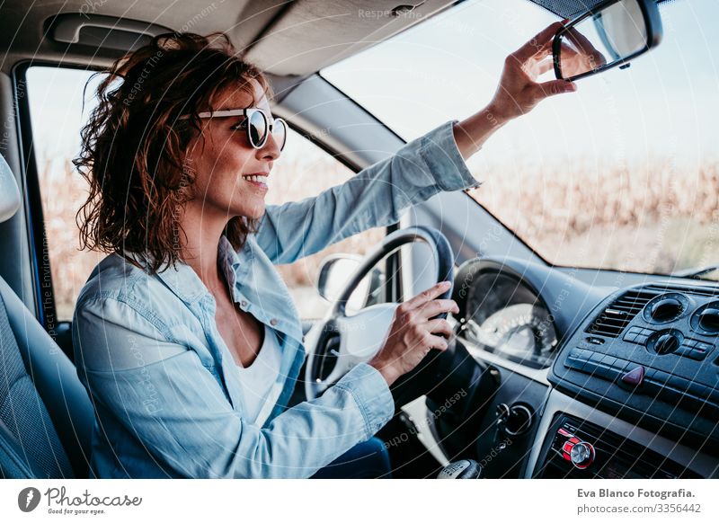 young beautiful woman driving a car and adjusting rear mirror. travel concept Woman Youth (Young adults) Driving Car Sunbeam Sunglasses Vacation & Travel