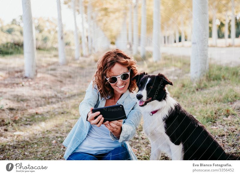 woman and beautiful border collie dog sitting in a path of trees outdoors. woman taking a selfie with mobile phone Woman Dog Selfie Cellphone Exterior shot