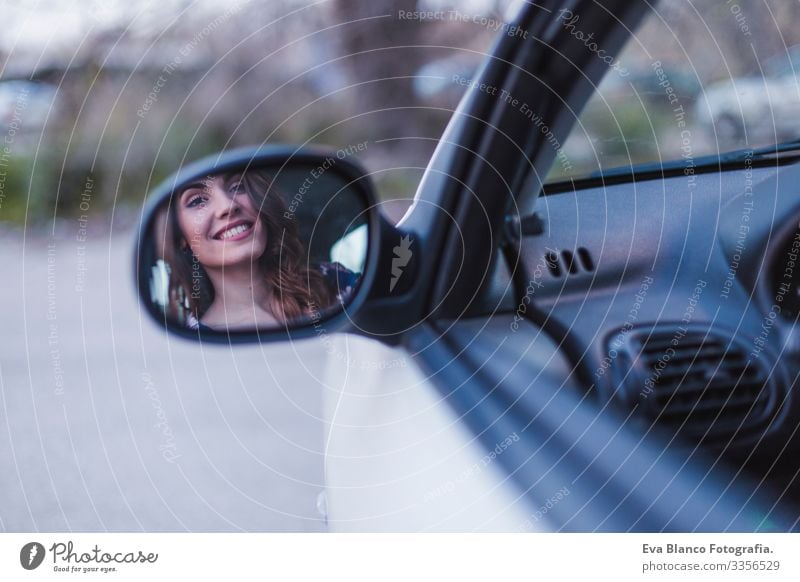 Young woman driving a car in the city. Portrait of a beautiful woman in a car, looking out of the window and smiling. Reflection in rear mirror. Travel and vacations concepts