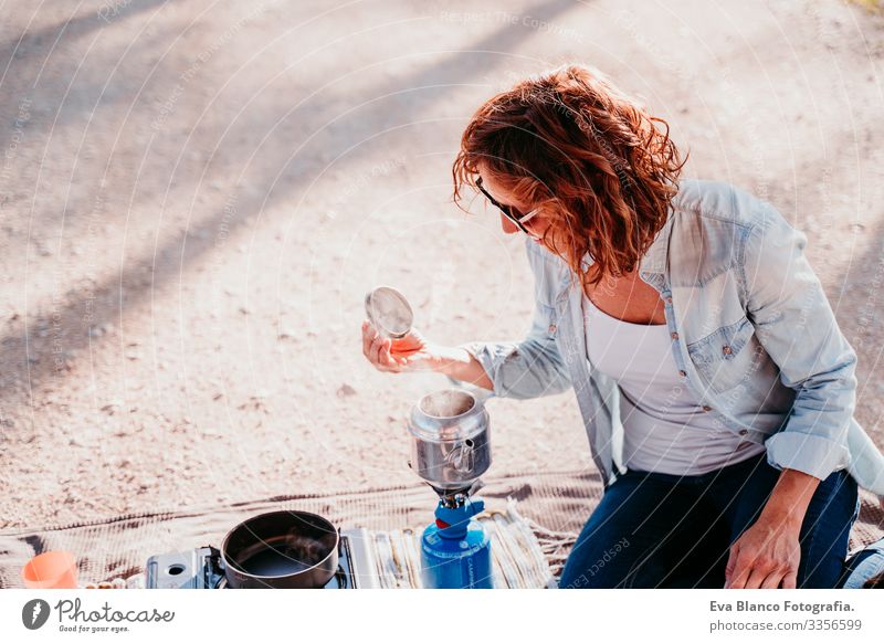 young woman preparing tea with pot and stove outdoors. camping concept Youth (Young adults) Woman Camping Pot Stove & Oven Sunset Hot Tea Teapot Coffee Day