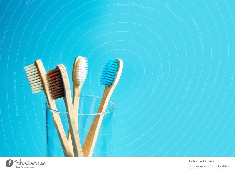 Wooden toothbrushes with a glass cup on a blue background. Lifestyle Medical treatment Wellness Bathroom Environment Nature Packaging Toothbrush Plastic Free