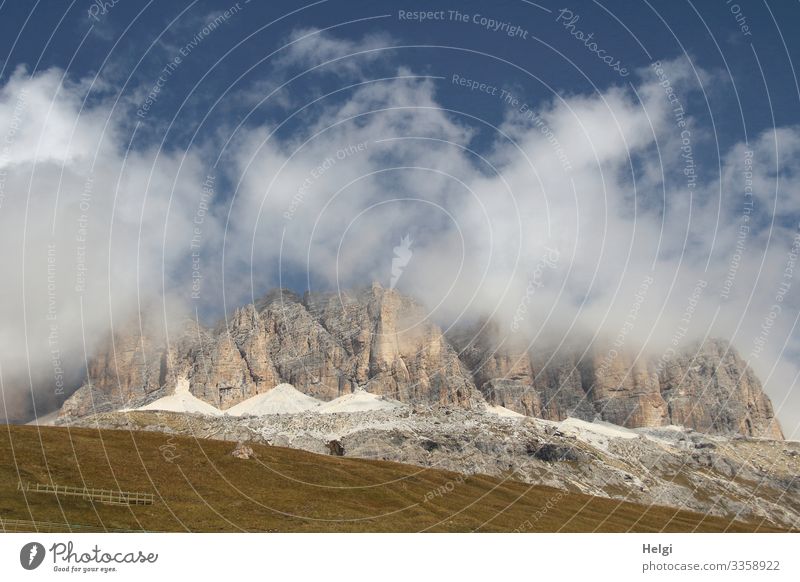 Mountains of the Alps are wrapped in thick clouds of blue sky Dolomites Sella yoke Autumn Meadow Clouds Sky Hiking Mountaineering Environment Nature Landscape