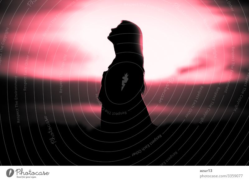 Youth woman soul at red sun meditation dreaming past times. Silhouette in front of sunset or sunrise in summer nature. Symbol for healing burnout therapy, wellness relaxation or resurrection.