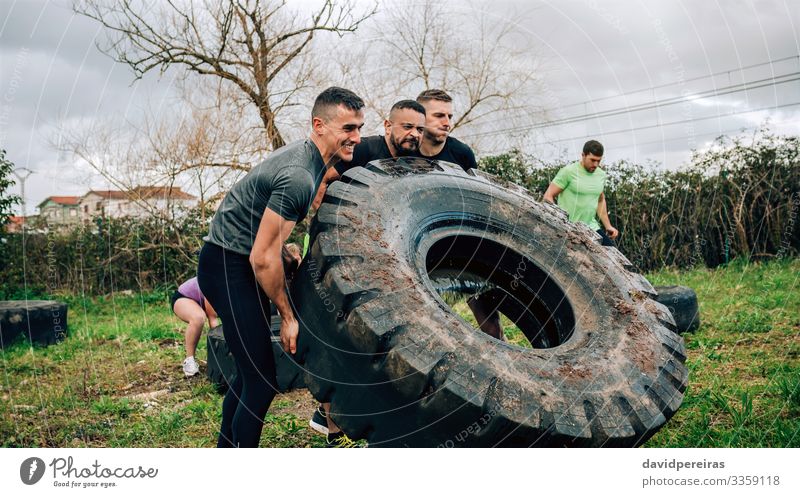 Participants in obstacle course turning truck wheel Sports Human being Man Adults Group Authentic Strong Black Power Effort Competition Teamwork team