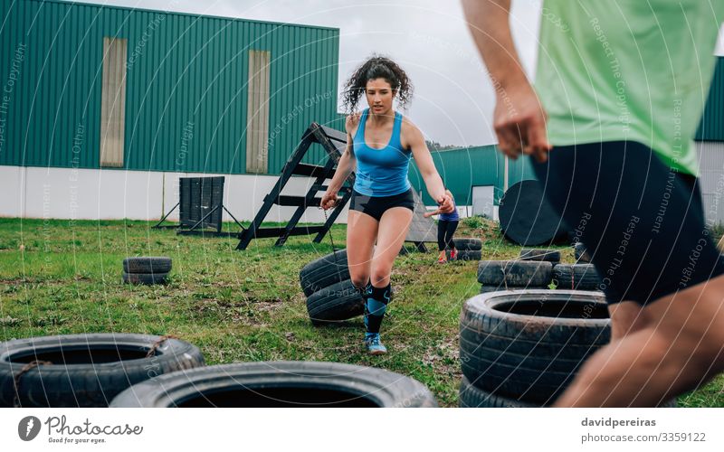 Female participant in obstacle course dragging wheels Sports Human being Woman Adults Man Grass Authentic Strong Power Effort obstacle course race Runner
