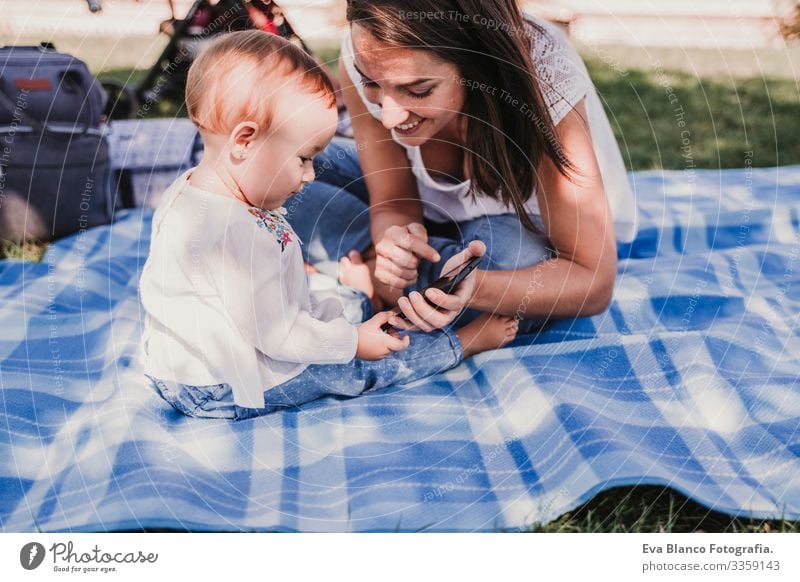 young mother and happy baby using mobile phone outdoors. technology concept Mother Baby Cellphone Technology Together Child Parenting Girl Joy Sunbeam Parents