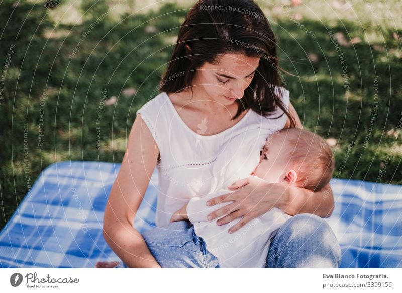 young mother playing breast feeding her baby girl outdoors in a park, happy family concept. love mother daughter Mother Baby Appease Milk Eating Child Parenting