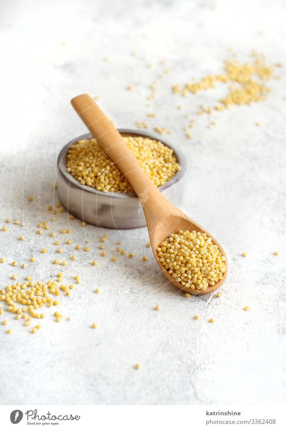 Raw dry hulled millet in a bowl with a spoon Vegetarian diet Diet Bowl Spoon Natural Yellow Gray Millet ceramic Dried fiber food healthy Ingredients Copy Space
