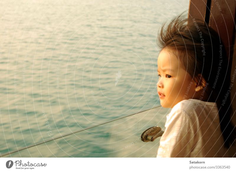 Asian girl stares out of the passenger boat window Lifestyle Summer Ocean Human being Child Girl Face Eyes 1 3 - 8 years Infancy Water Wind Waves Passenger ship