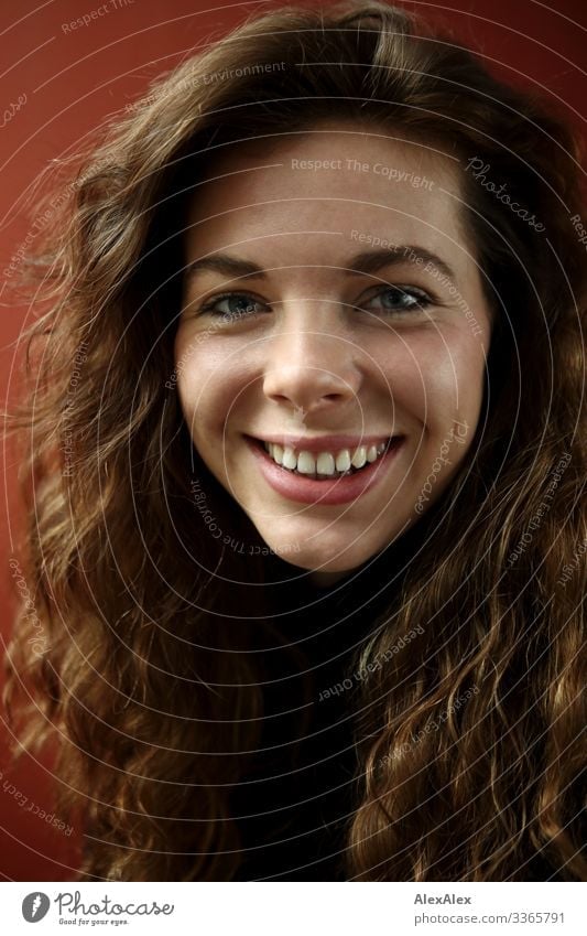 Portrait of a smiling young woman with dimples in front of a red wall Lifestyle Style Joy already Young woman Youth (Young adults) Hair and hairstyles Face