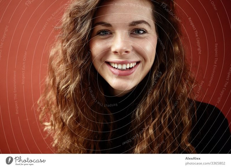 Portrait of a smiling young woman with dimples in front of a red wall Living or residing Young woman Youth (Young adults) Face 18 - 30 years Adults Sweater