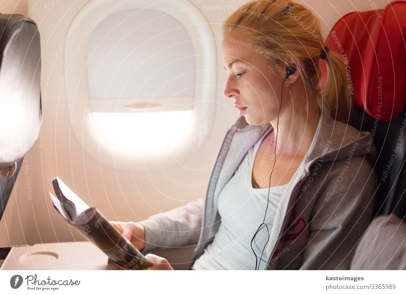 Woman reading magazine and listening to music on airplane. Lifestyle Relaxation Reading Vacation & Travel Trip Entertainment Music Economy Business Human being