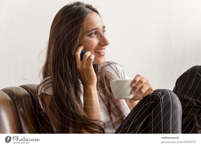 Young Woman Talking on Phone and Holding Coffee Cup phone conversation smile talking on phone female girl young adult day natural beauty real life